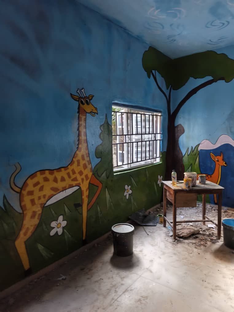 Classroom mural of a giraffe, a deer and a tree on a blue wall