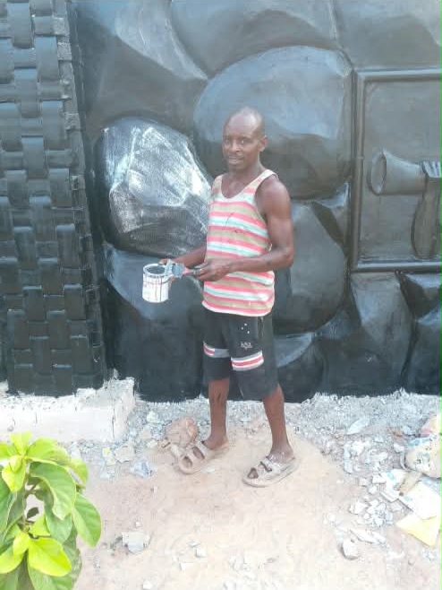 Craftsman painting a large black rock-relief wall